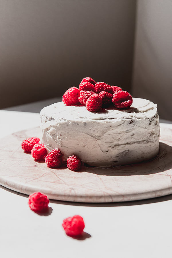 An entire gluten free chocolate raspberry cake that is iced and topped with raspberries. 
