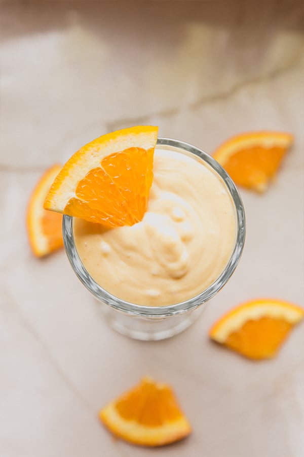 An overhead shot of a creamsicle frosty topped with orange slices.