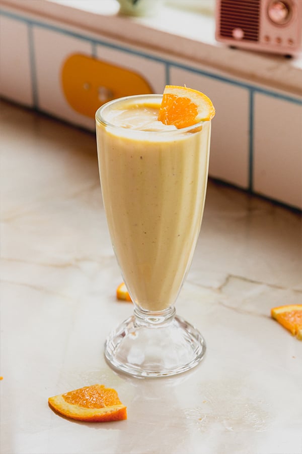 A cup of creamiscle frosty topped with orange slices ready to be enjoyed.