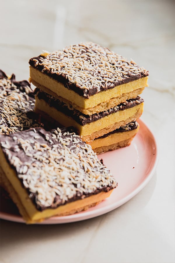 A stack of lemon coconut s'mores bars stacked on a plate.