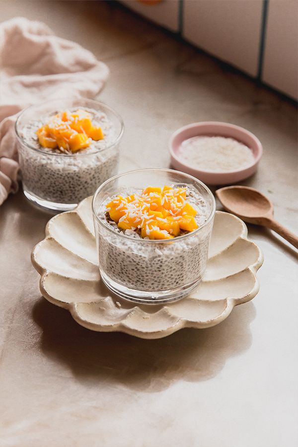 Two cups of mango sticky rice chia pudding sitting on the counter.