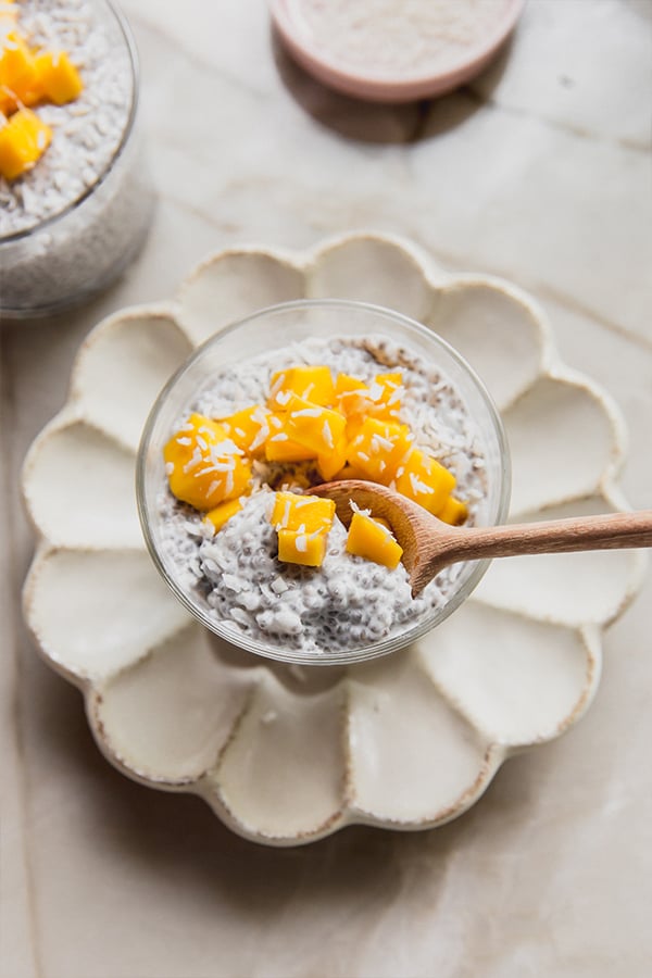 A spoon taking a bite out of a cup of mango sticky rice chia pudding.