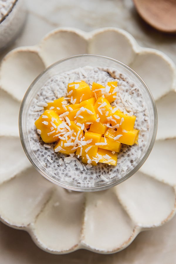 A cup of mango sticky rice chia pudding sitting on the counter.