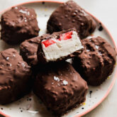 Dairy free strawberry crunch bites on a plate, with one cut in half to show the ice cream and strawberry slice.