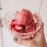 Strawberry pink drink sorbet scooped into a glass dish and topped with crushed freeze dried strawberries.