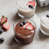 Chocolate and vanilla pudding in bowls topped with berries.