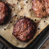 Air fryer burgers cooked in the air fryer with vented parchment paper.