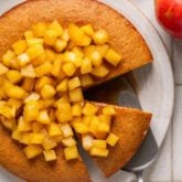 Honey apple cake with a slice taken out of it and topped with apples.