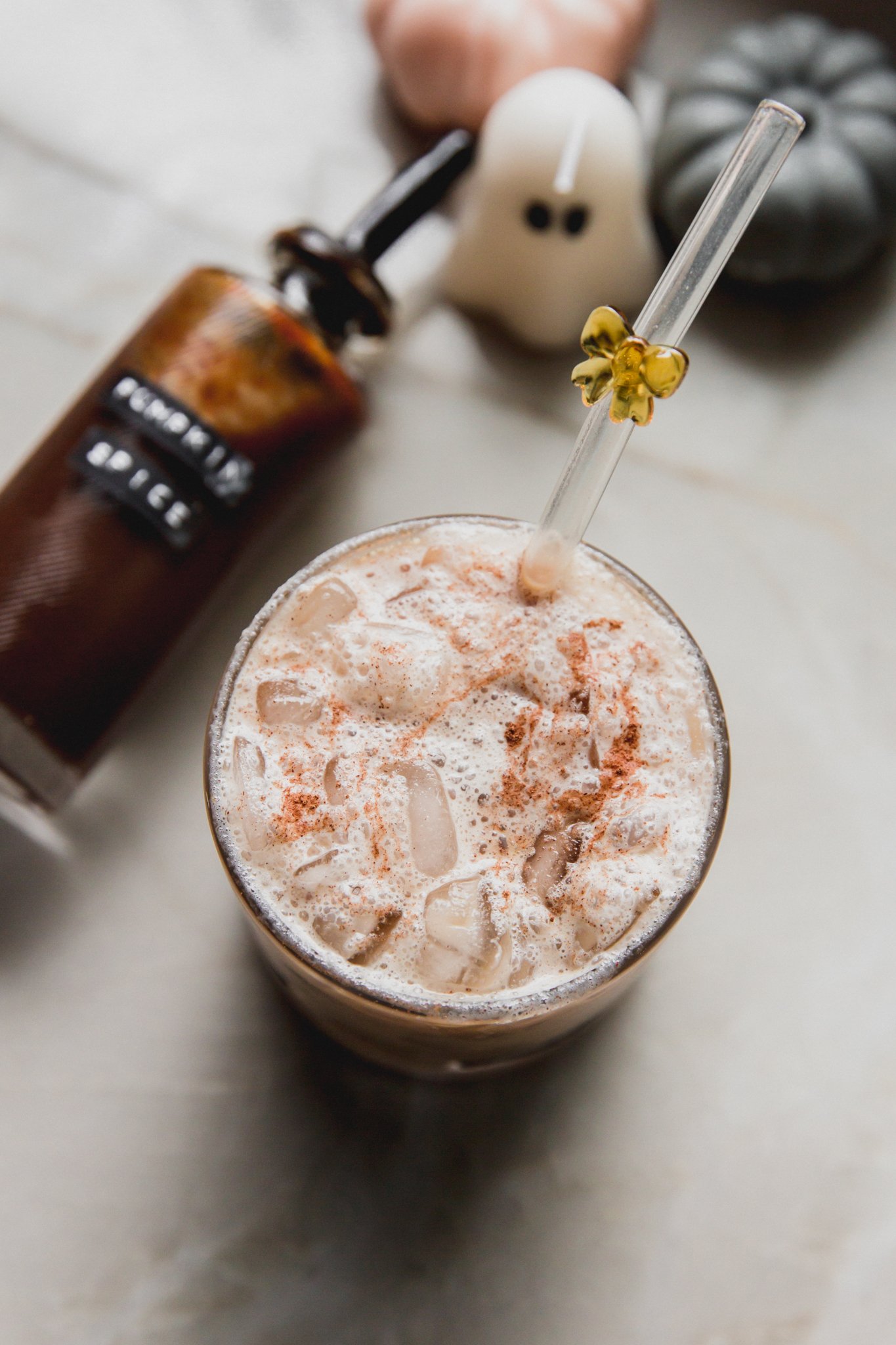 Pumpkin spice latte with the syrup bottle sitting next to it. 