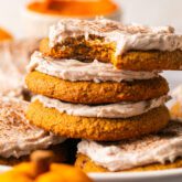 Three pumpkin spice cookies topped with frosting stacked on top of eachother.