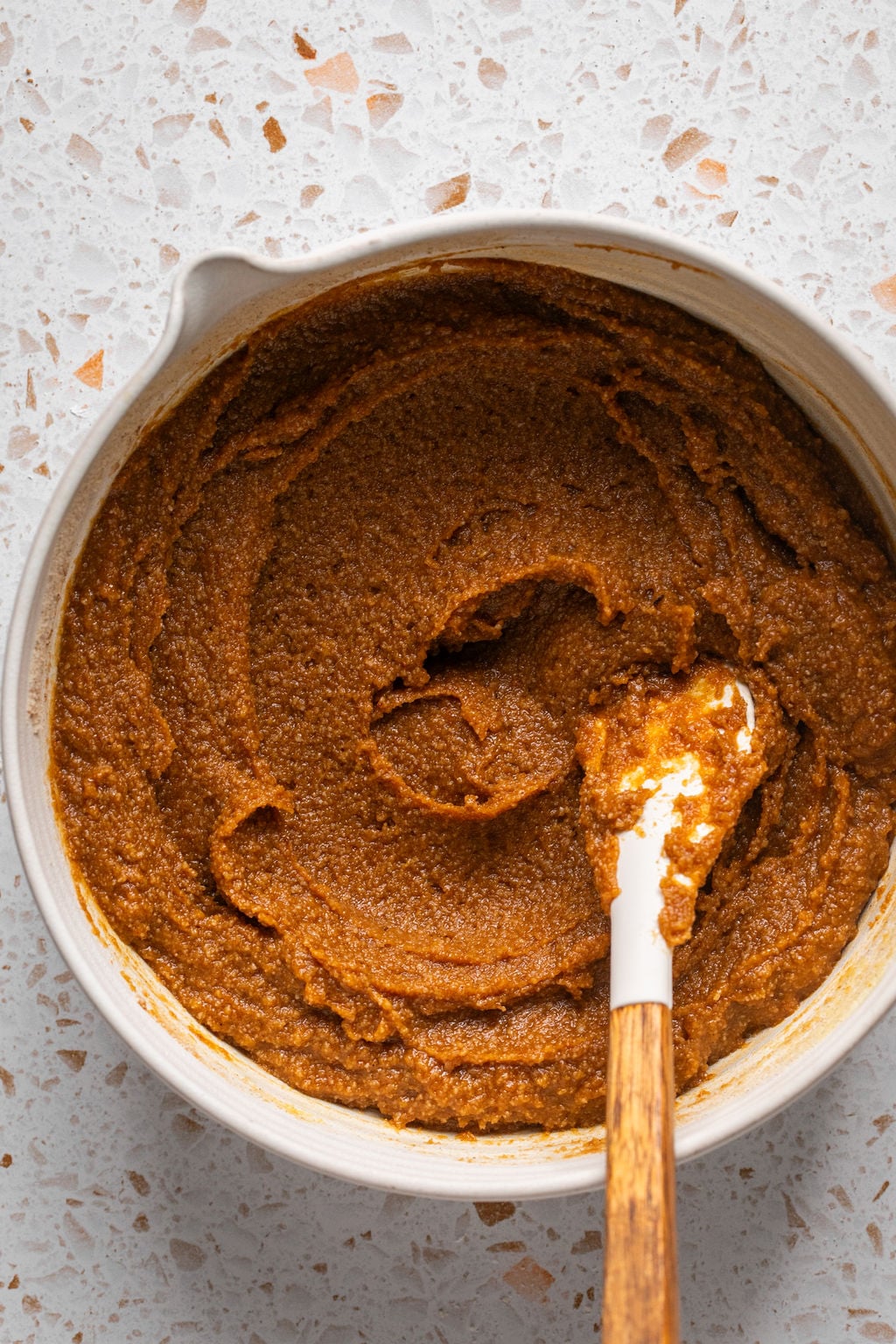 Pumpkin cookie batter in a bowl with a spoon.