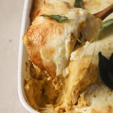 Butternut squash lasagna in a pan, with one roll up being pulled up with a spatula.
