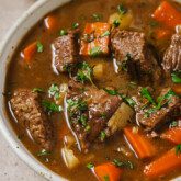 Dutch oven beef stew in a bowl topped with parsley.
