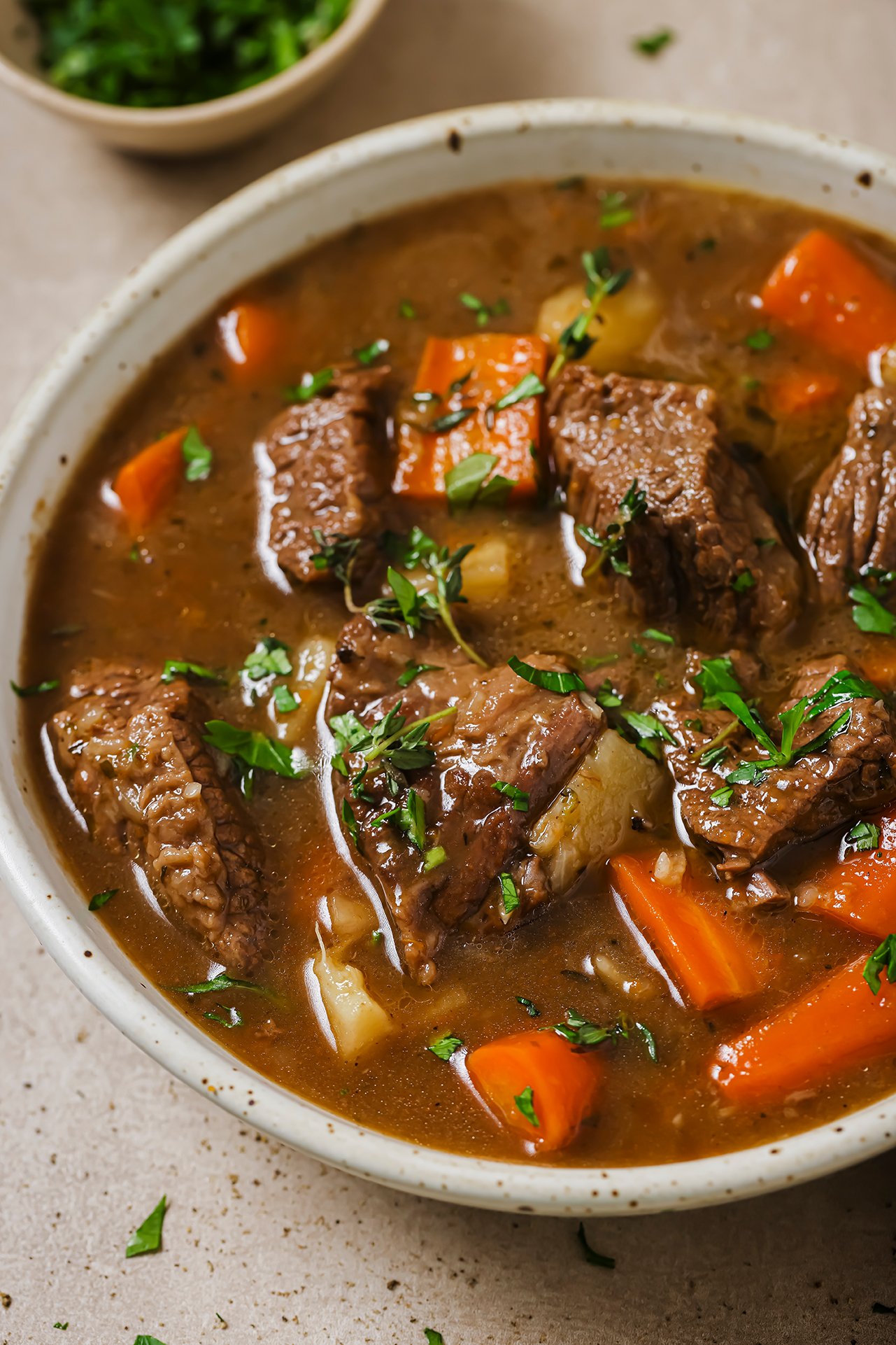 Dutch oven beef stew in a bowl topped with parsley.