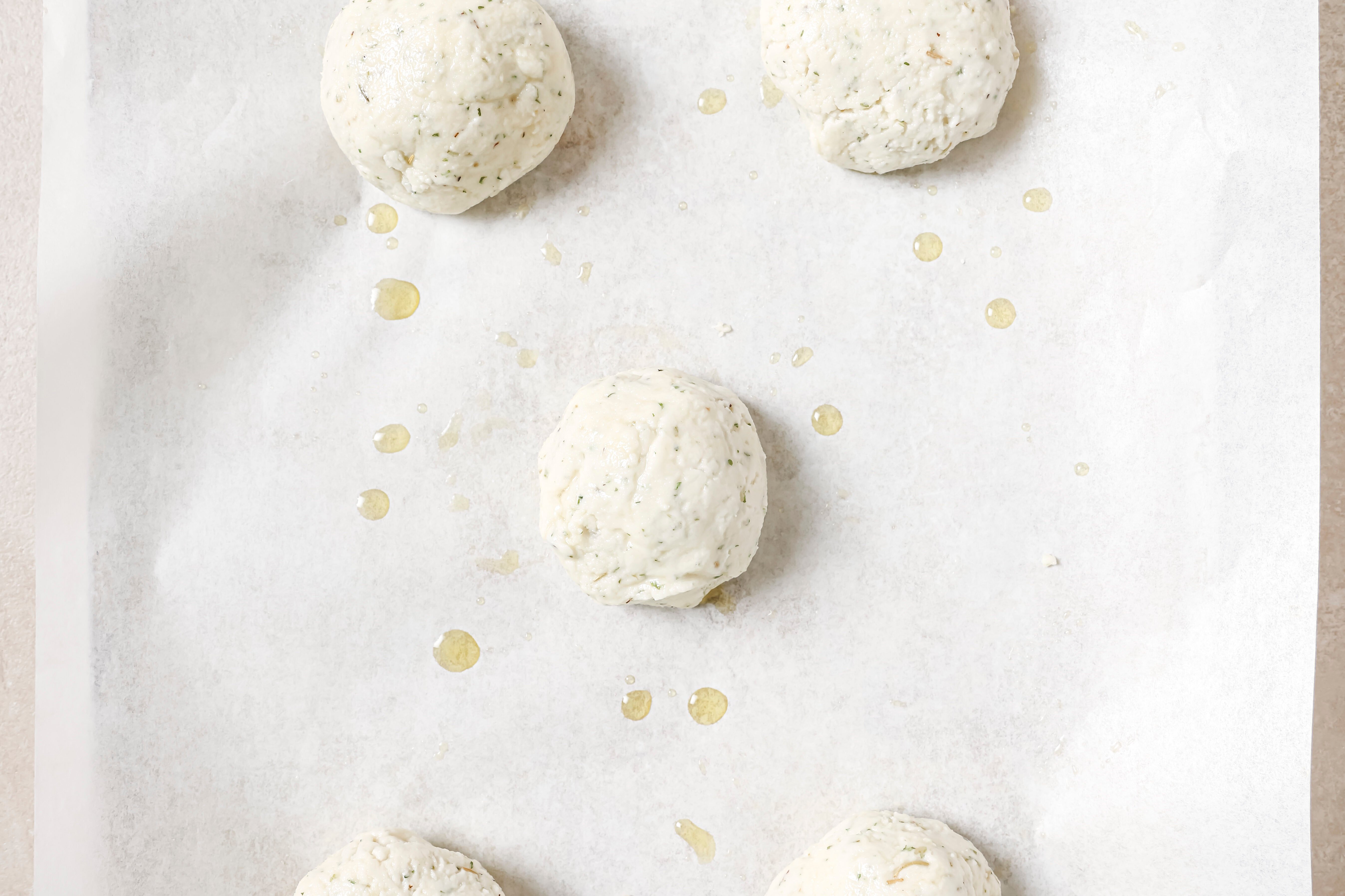 Five uncooked bread rolls on a baking sheet