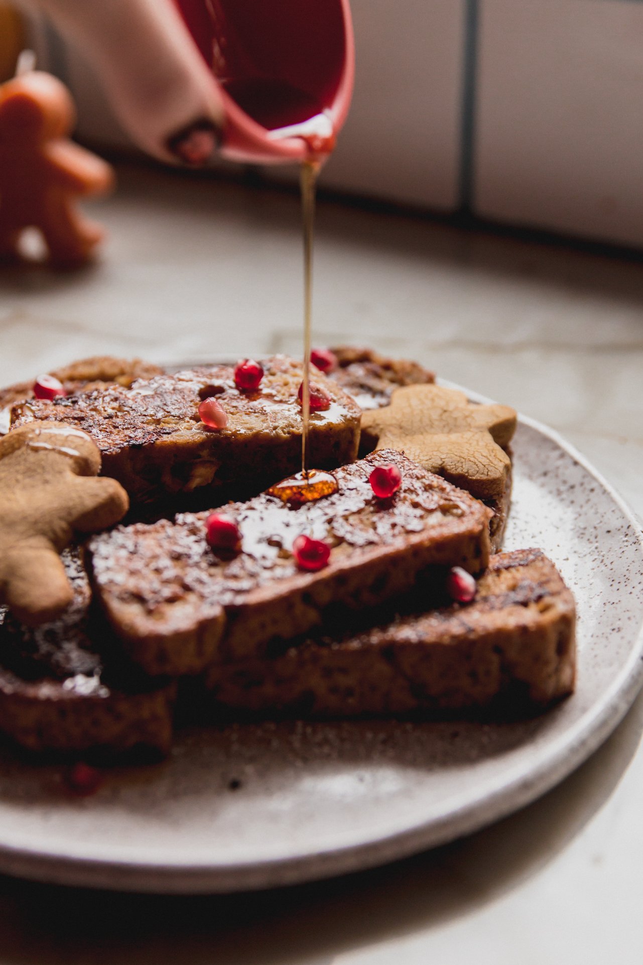 Gingerbread french toast on a plate with maple syrup being poured over.