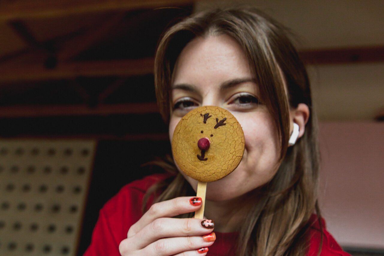 Michelle holding a reindeer gingerbread cookie up to her face.