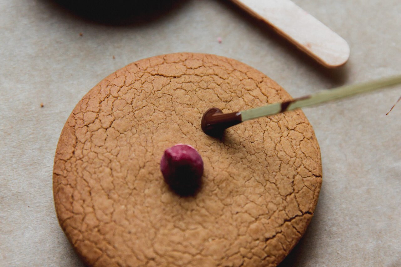 Decorating the gingerbread cookies with a red nose and adding the antlers.