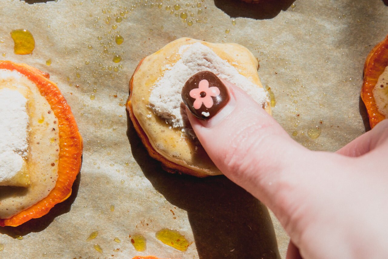 A thumb pressing the marshmallow into the sweet potato bite.