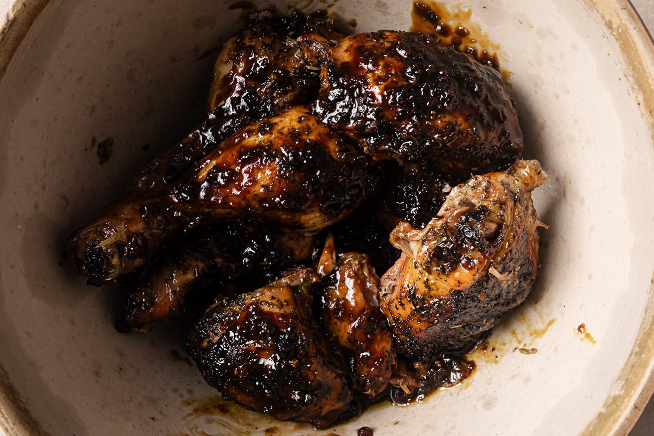 Turkey wings in a bowl topped with an orange glaze. 