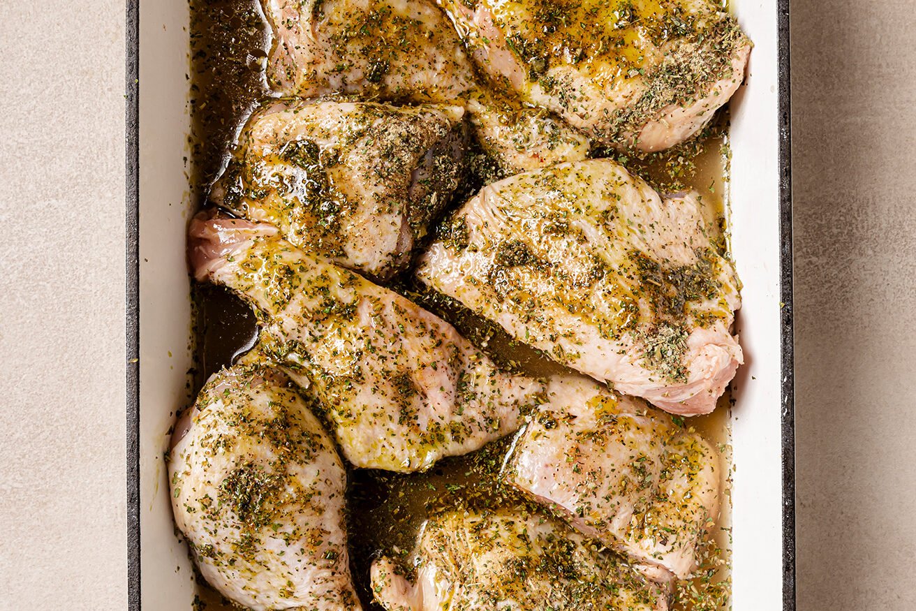 Raw turkey wings in a baking dish with chicken broth.