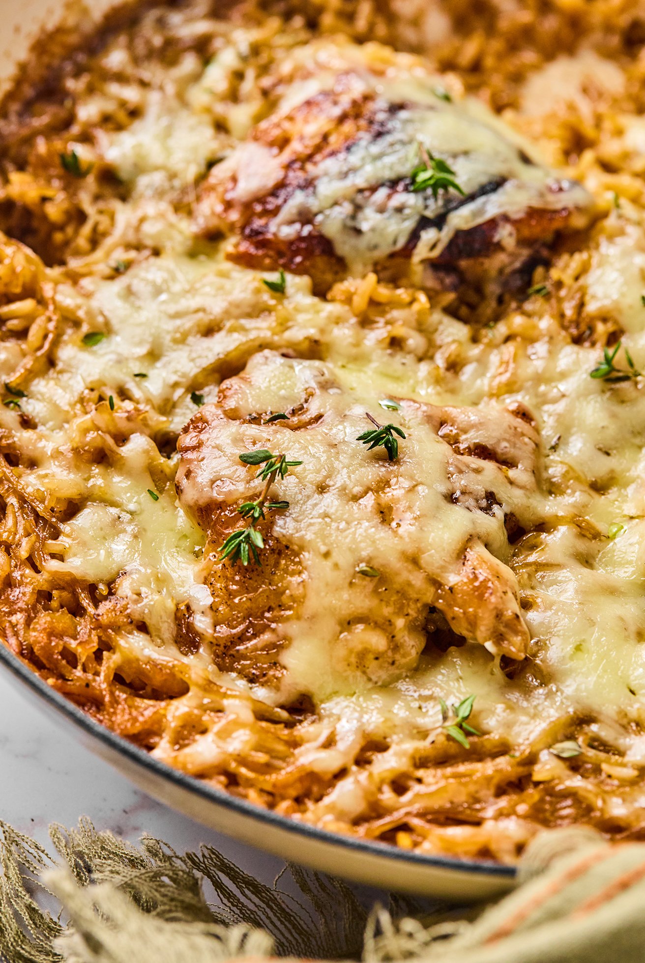 French onion chicken and rice in a large cast iron pan topped with fresh thyme.