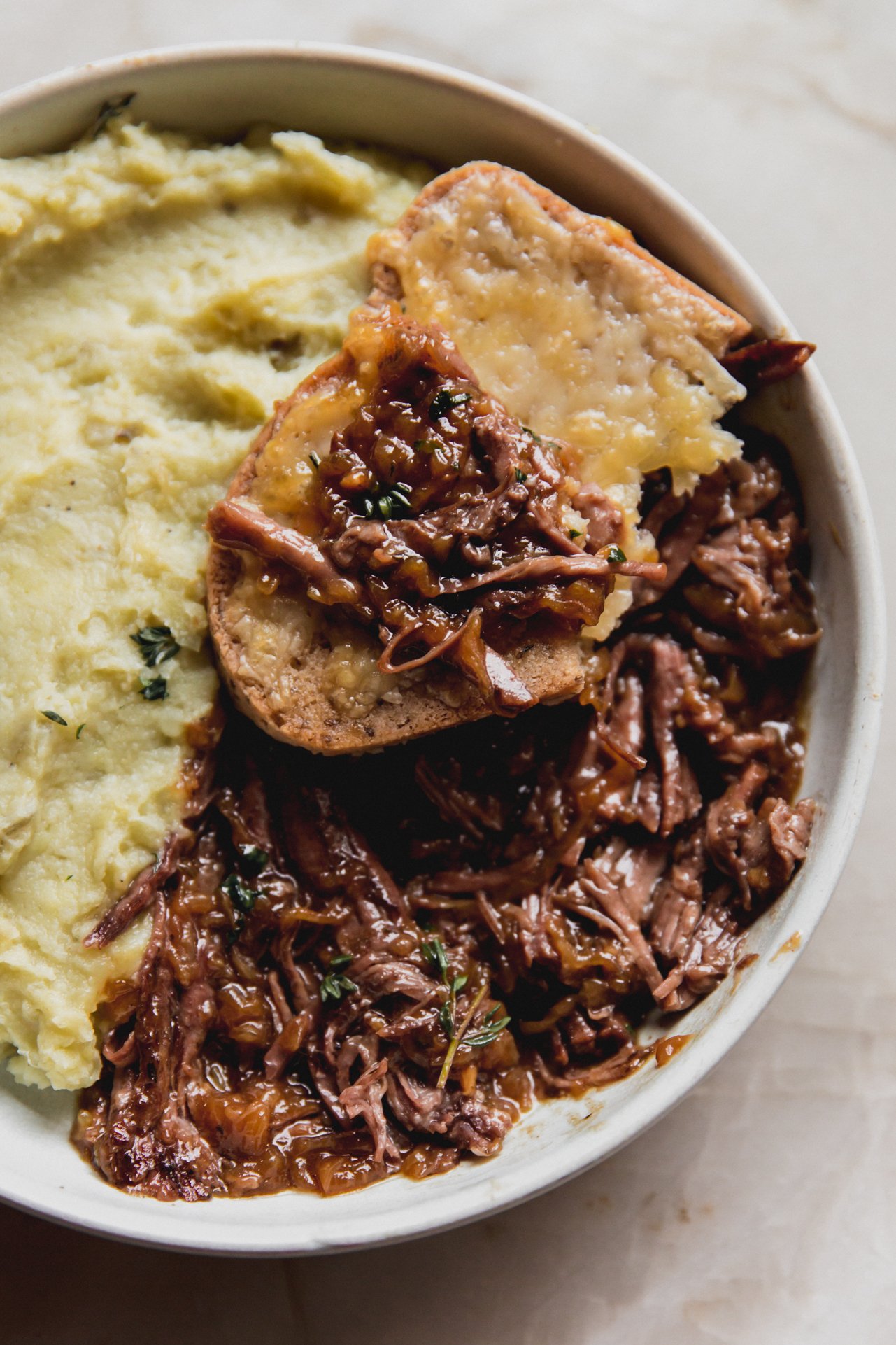 French onion pot roast with a piece of toast topped with some roast. 