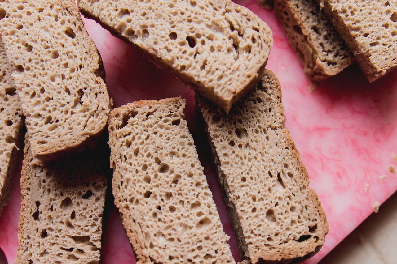 Gluten free bread sliced in half on a cutting board.