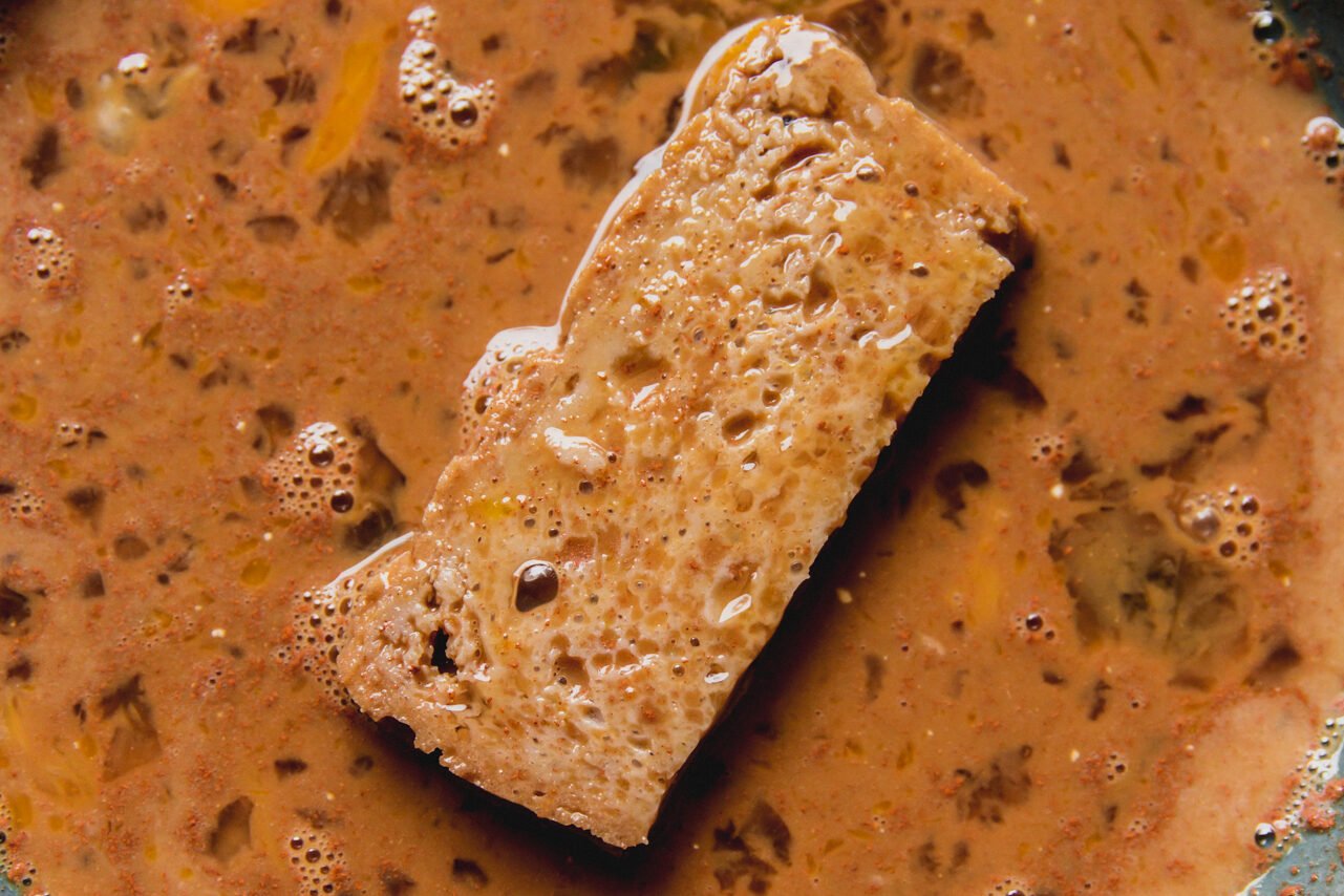 gluten free bread dipped in a bowl of french toast batter.