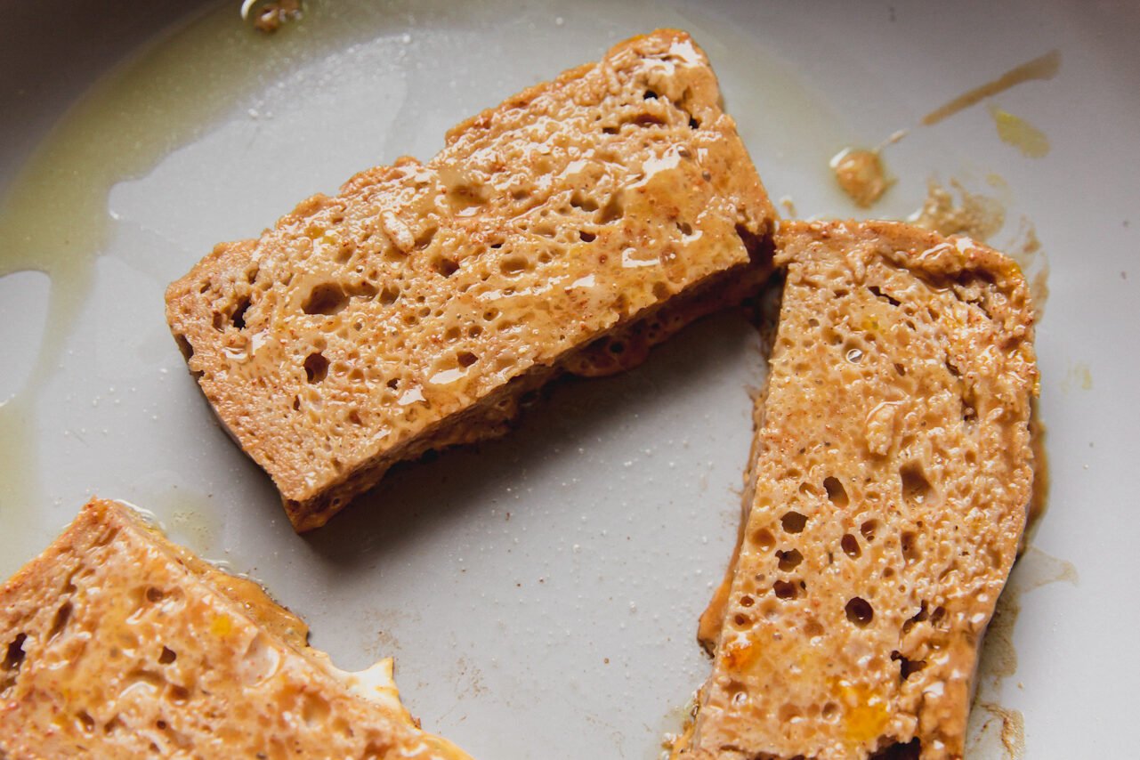 Gluten free french toast sticks frying in a pan.