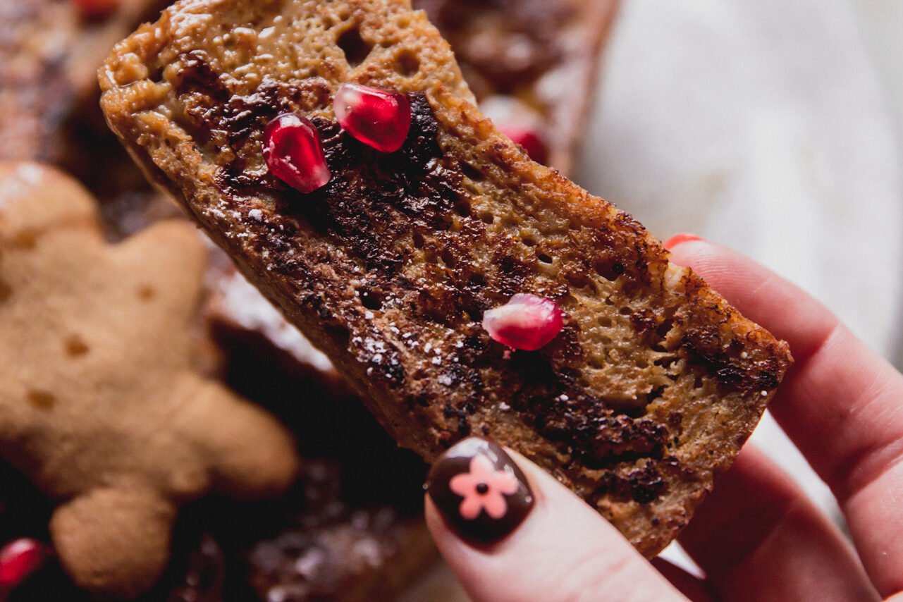 Cooked gluten free french toast sticks topped with pomegranate seeds. 