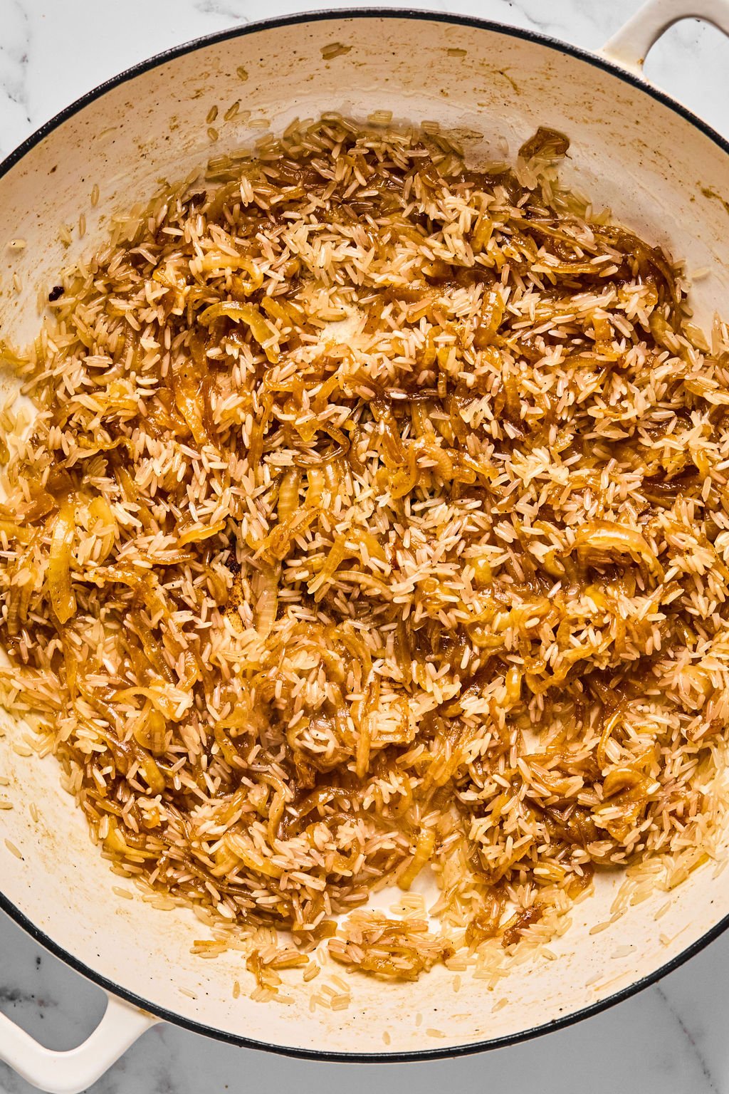 The caramelized onions and toasted rice in a pan.