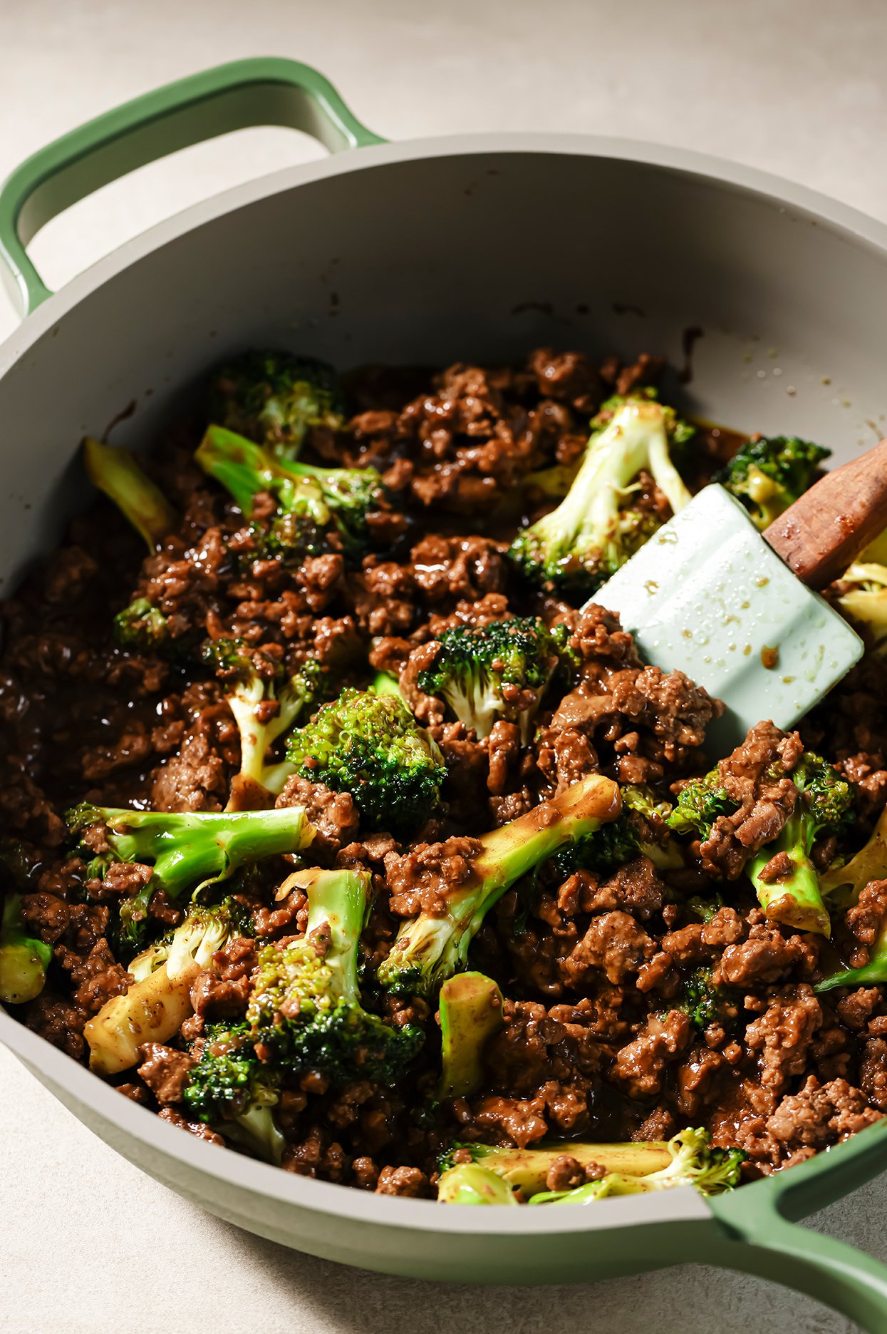 Ground beef and broccoli in a large green pan.