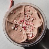 Peppermint ninja creami topped with candy pieces in a plastic container.