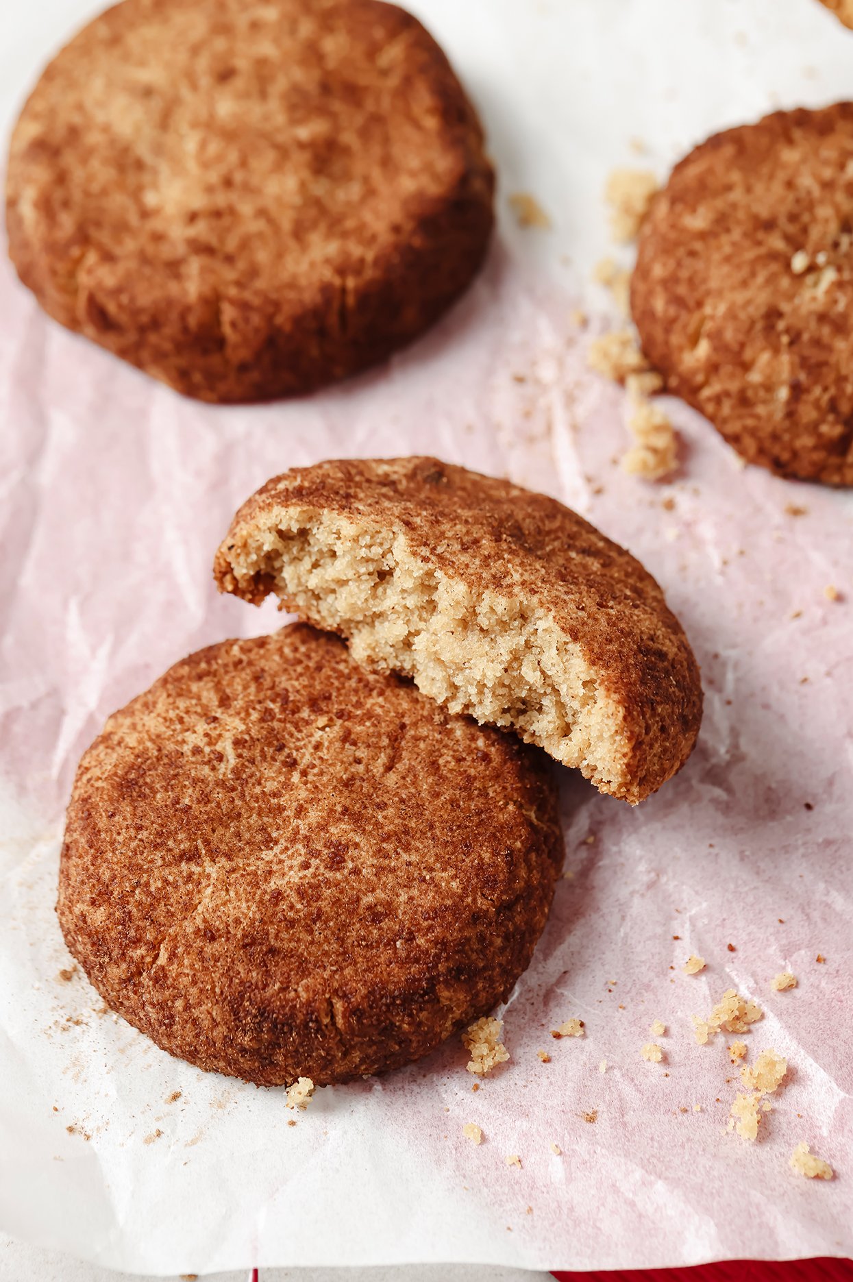 Snickerdoodle cookies on a baking tray, with one broken in half.