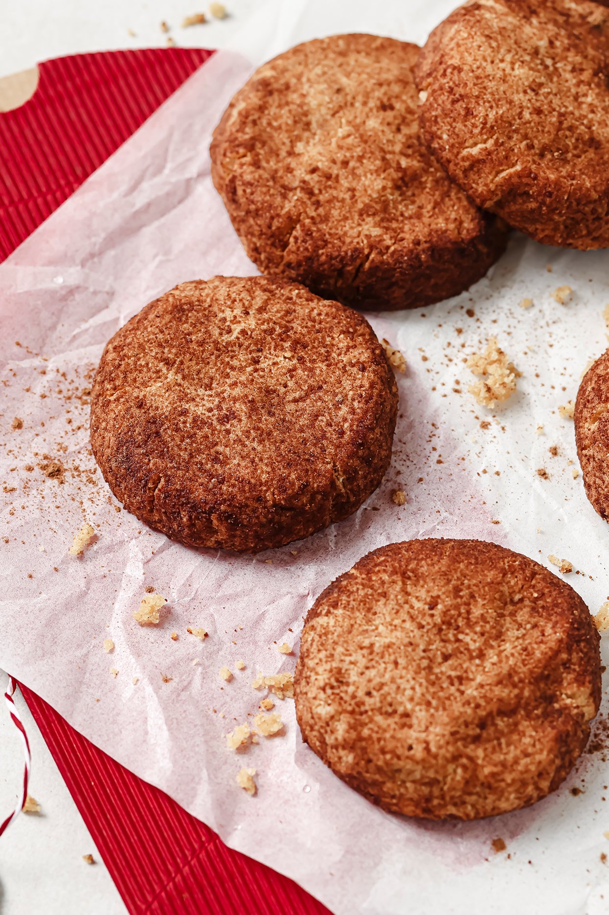 Snickerdoodle cookies on a baking tray with crumbs and sugar.