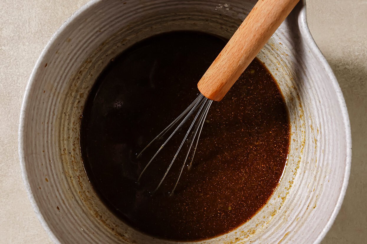 Sauce for ground beef and broccoli in a bowl with a whisk. 