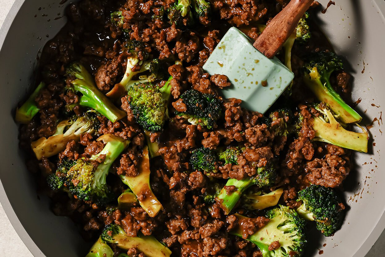 Ground beef and broccoli cooking in a pan with sauce.