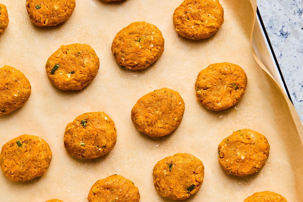 Uncooked sweet potato chicken poppers on a sheet pan. 