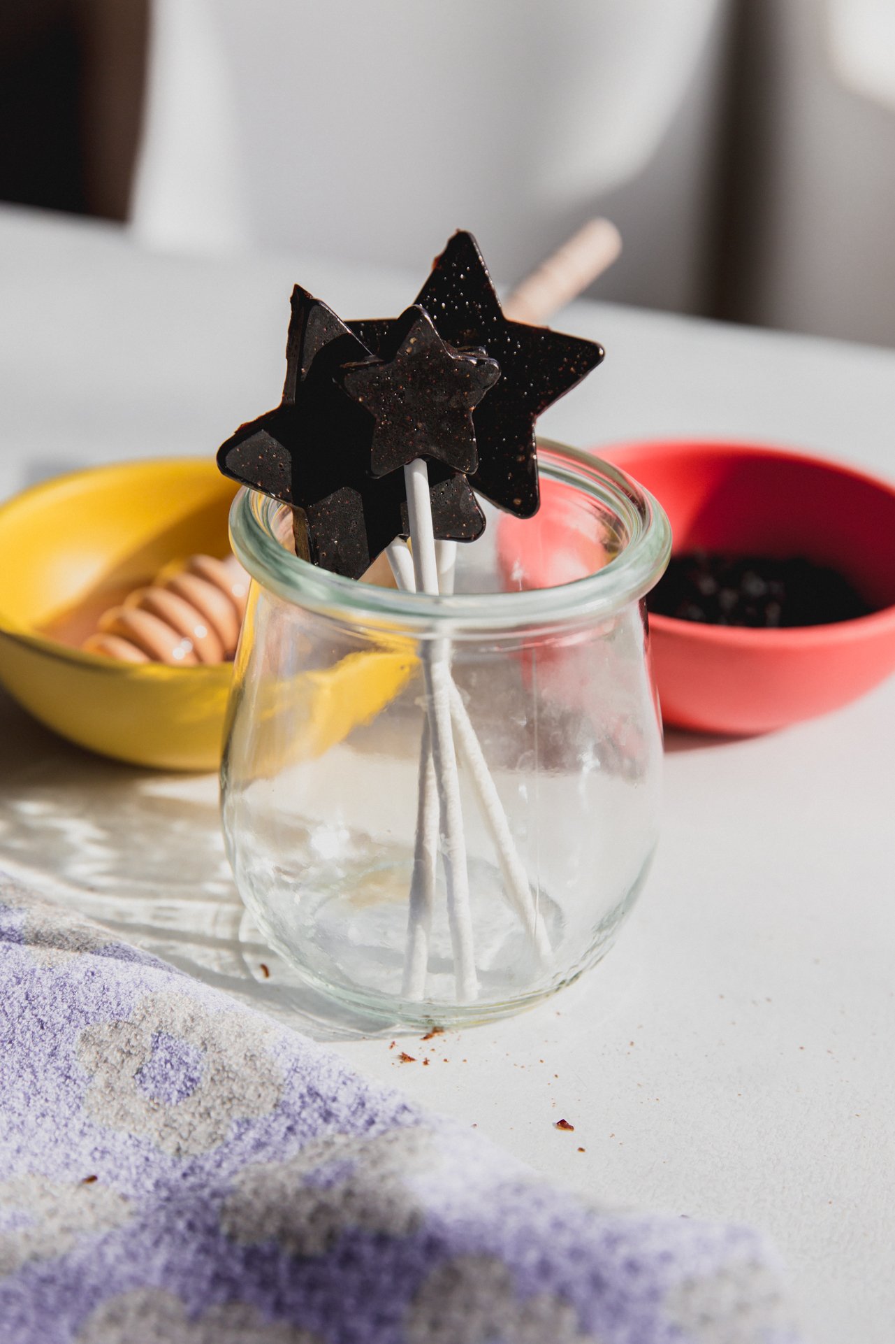 Three star shaped elderberry lollipops in a glass jar.