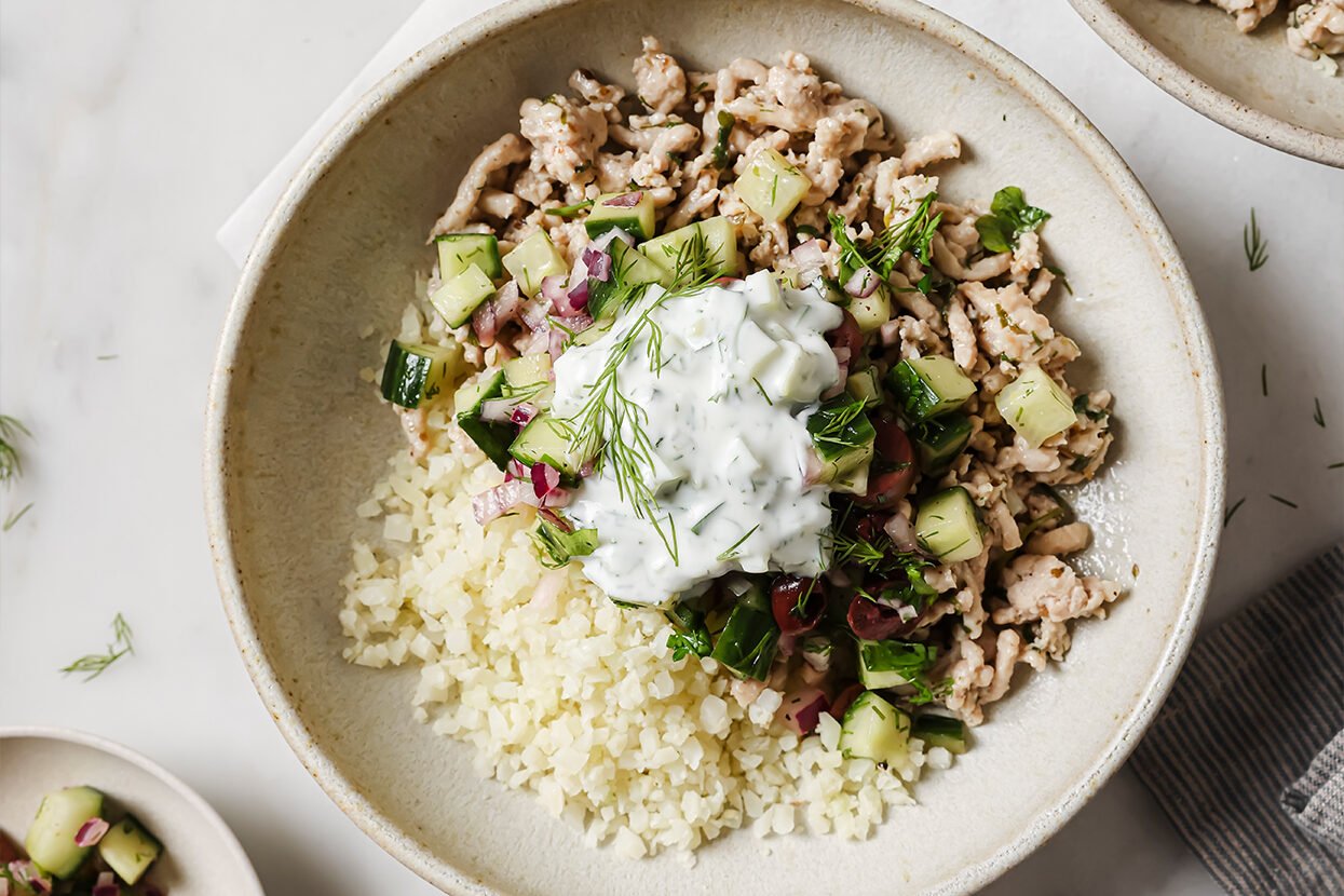 Greek ground chicken bowl with extra ingredients on the side.