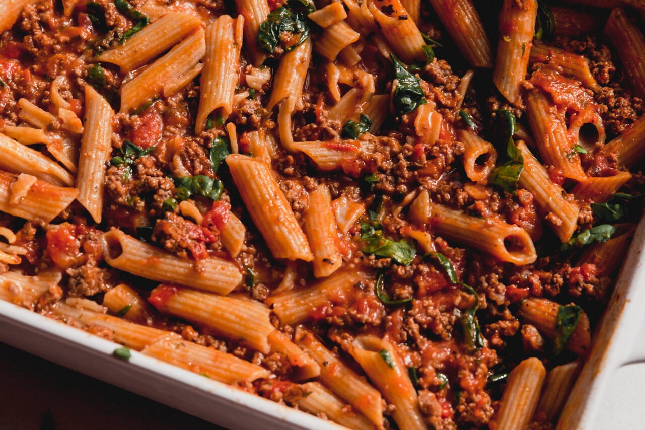 Cooked no boil pasta bake in a casserole dish with spinach stirred in.