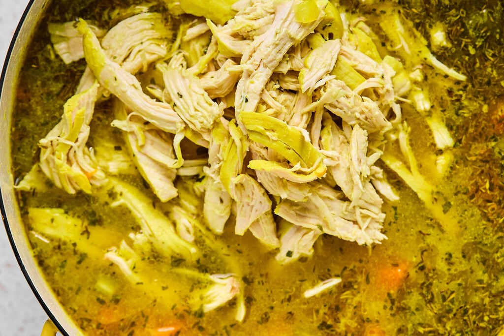 The shredded chicken on top of the soup ready to be mixed.