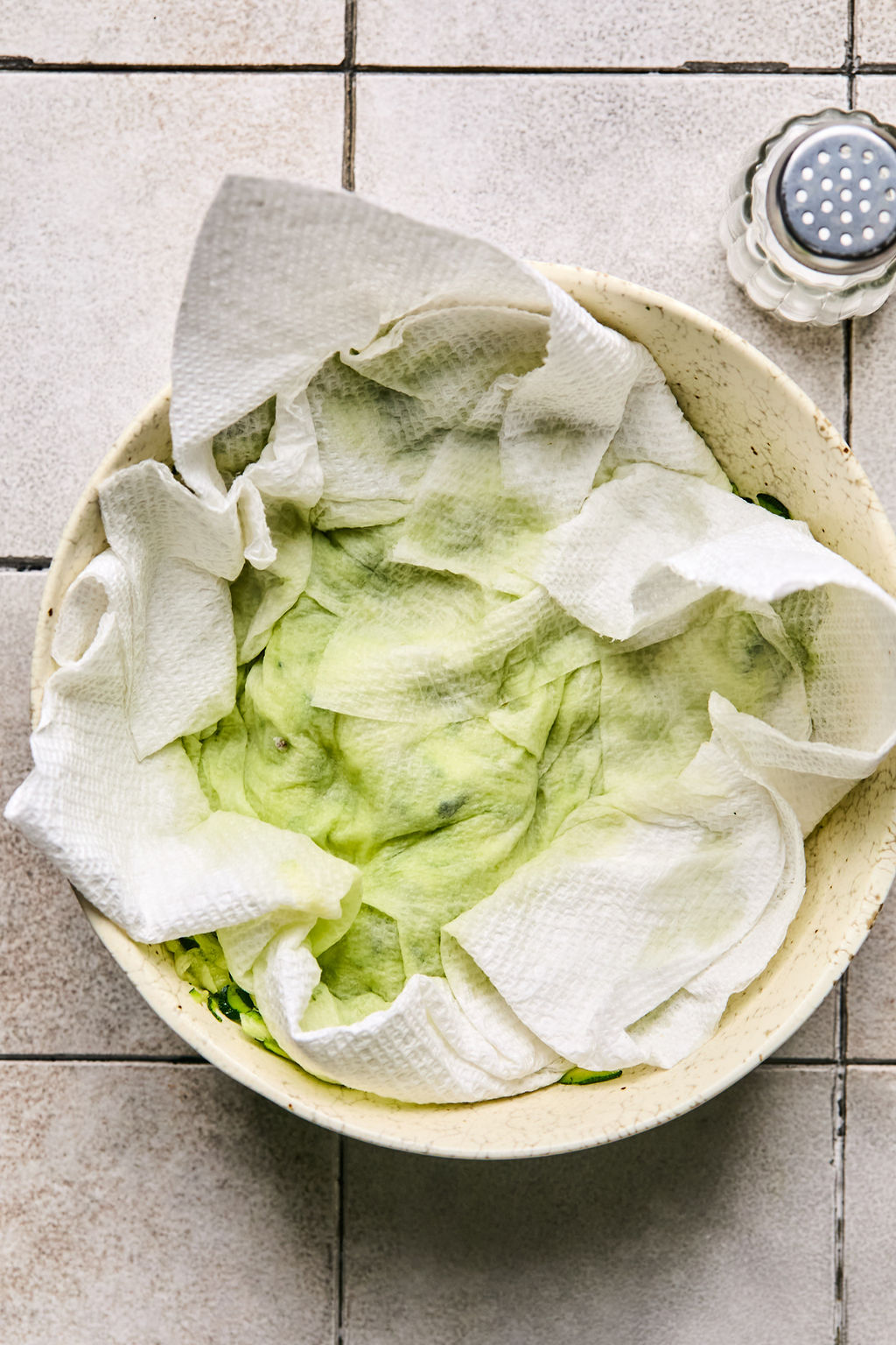 shredded zucchini in a bowl with a paper towel