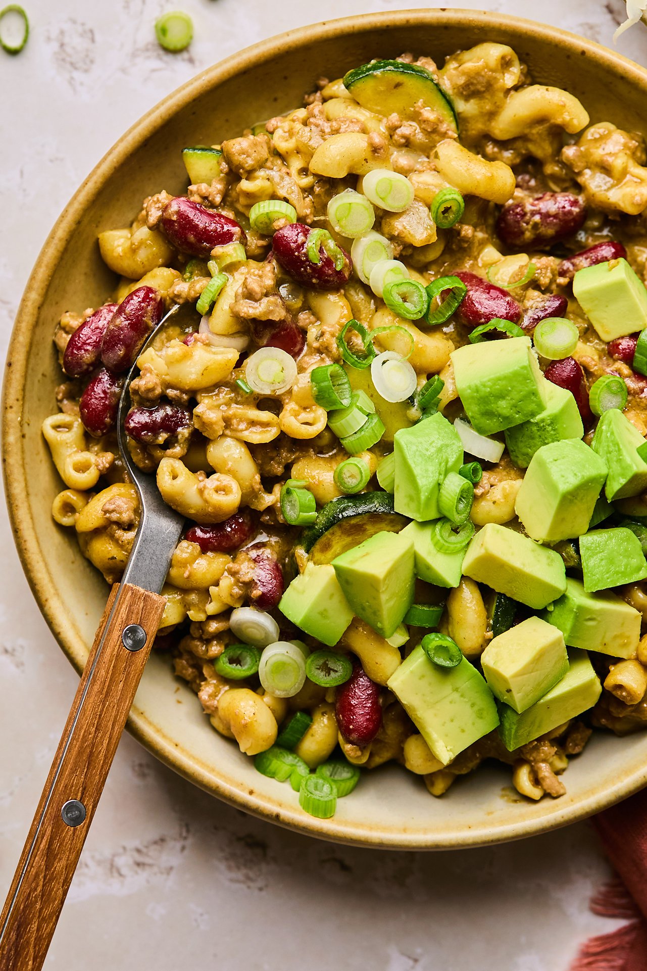 gluten free chili mac in a bowl with avocado and green onion