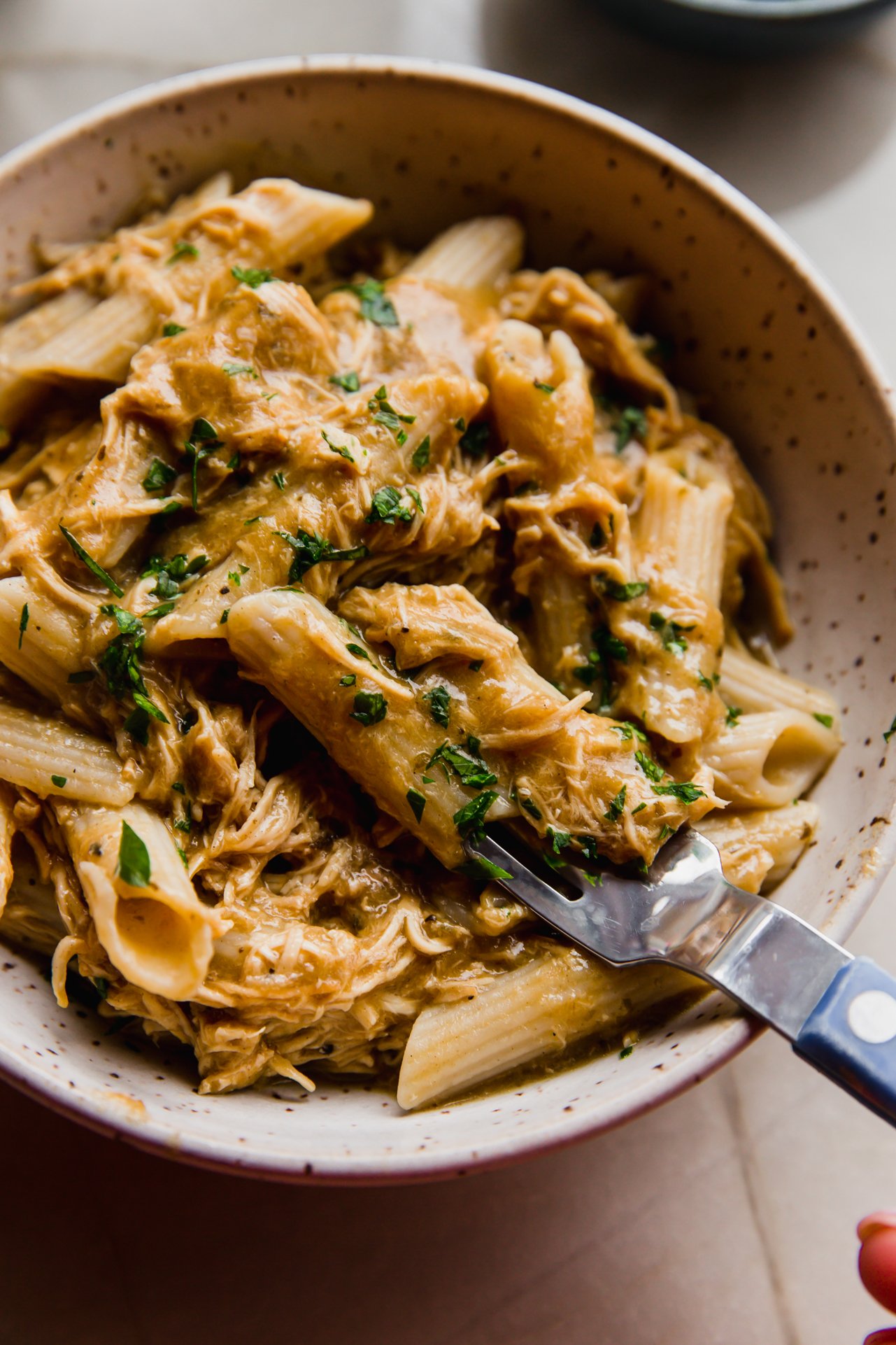 Creamy slow cooker pasta in a bowl topped with parsley.