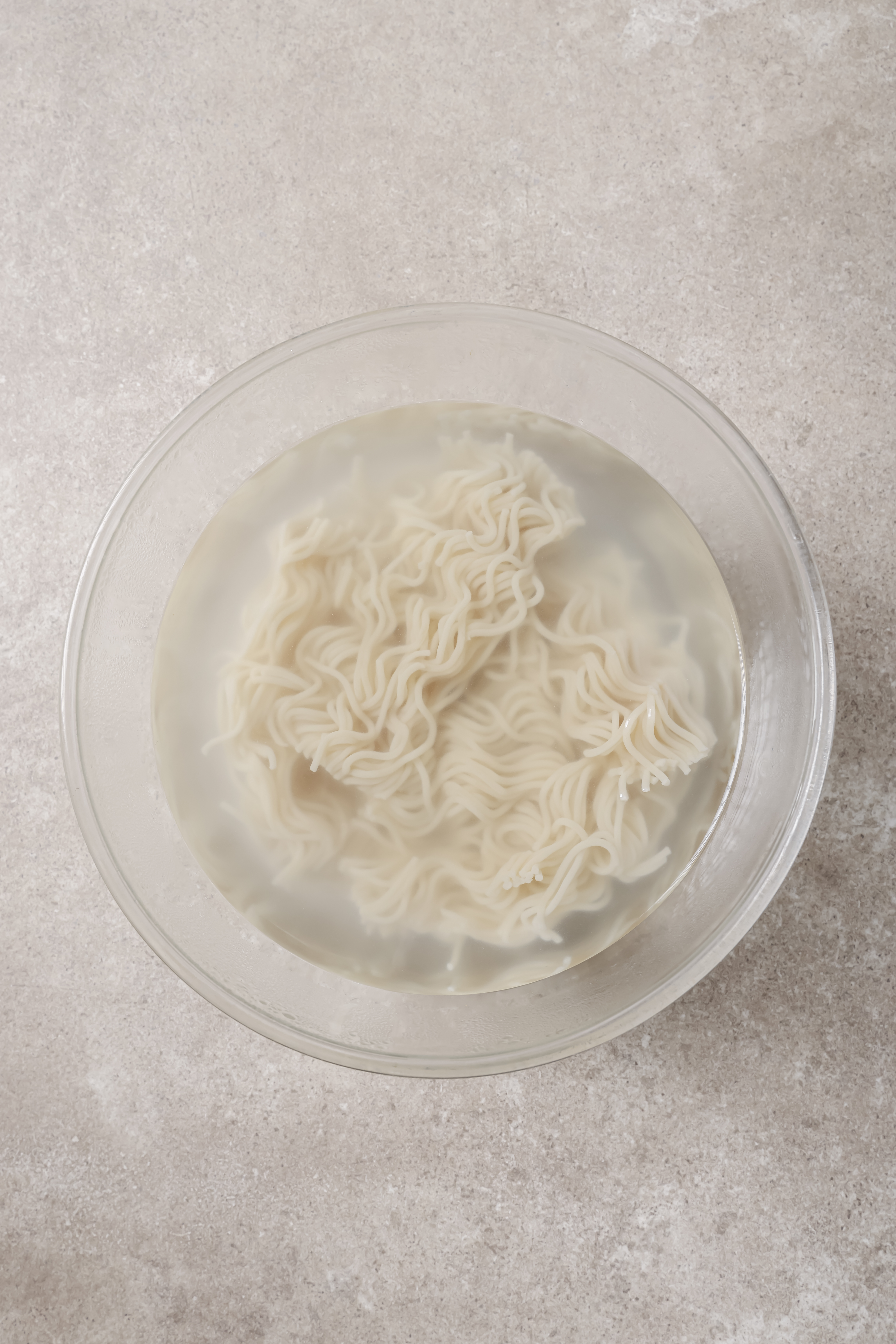 ramen noodles softening in a bowl of hot water