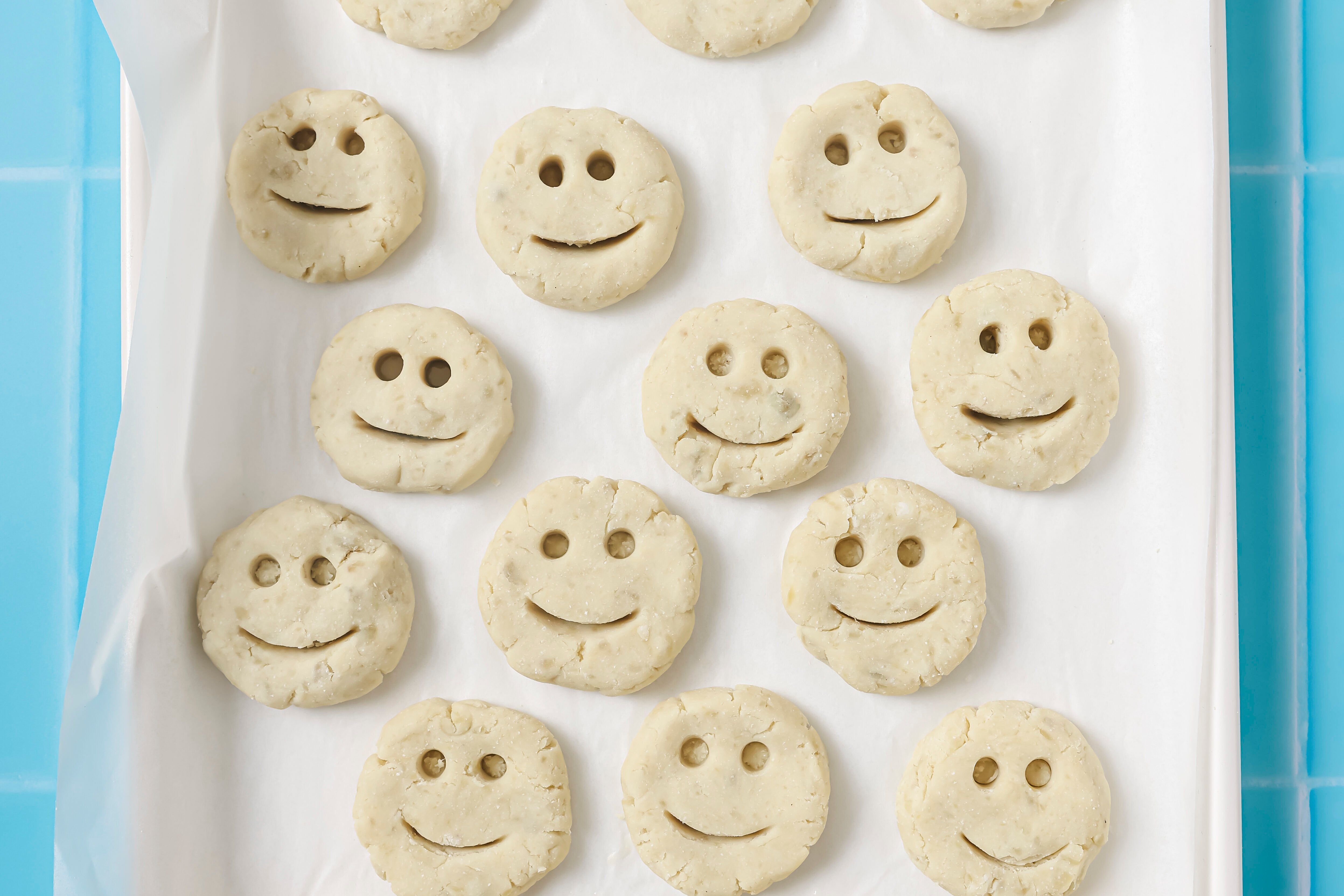 Smiley fries uncooked on a baking sheet.