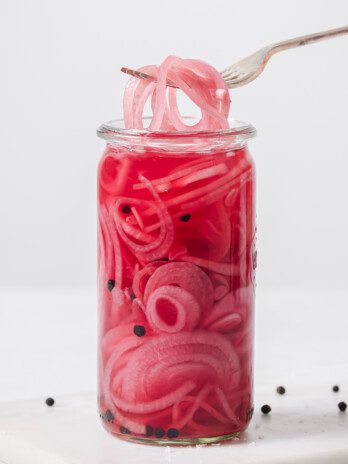Apple cider vinegar pickled onions in a jar with a fork.