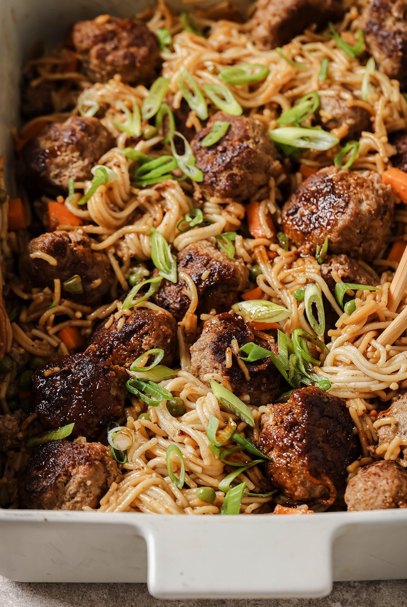 Teriyaki meatballs and ramen in a casserole bowl, topped with sauce.